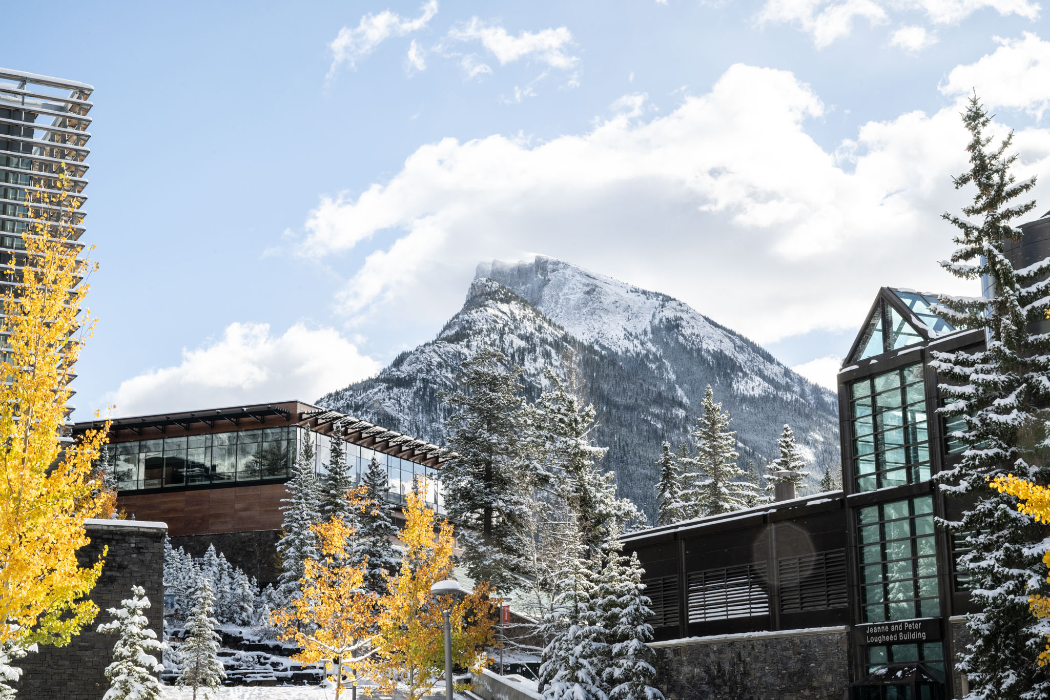 Banff Centre campus with golden autumn trees and fresh snow beneath a mountain peak.